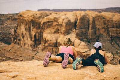 两个女人脸朝下躺在岩壁上，白天俯瞰岩壁